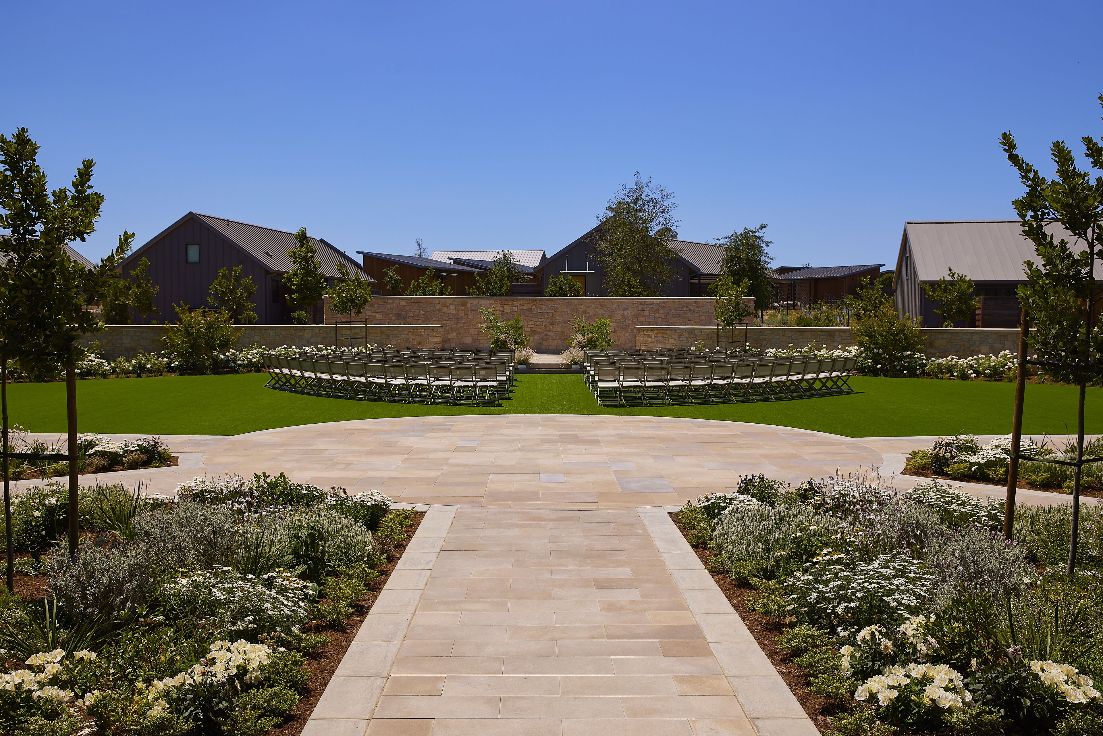 A landscaped courtyard with a central pathway leading to a seating area, surrounded by buildings with a modern architectural style.