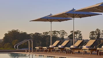 Una piscina al aire libre, camas de piscina con cargo, sombrillas