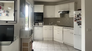 Een moderne keuken met witte kasten, een inbouwoven, een magnetron en een koelkast.
