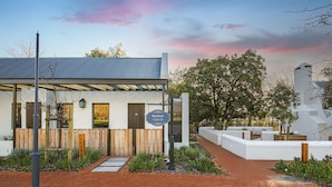 A modern building with a metal roof, a wooden fence, and a paved entrance.
