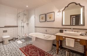 Une salle de bain comprenant une baignoire sur pieds, des toilettes, un lavabo et une douche.