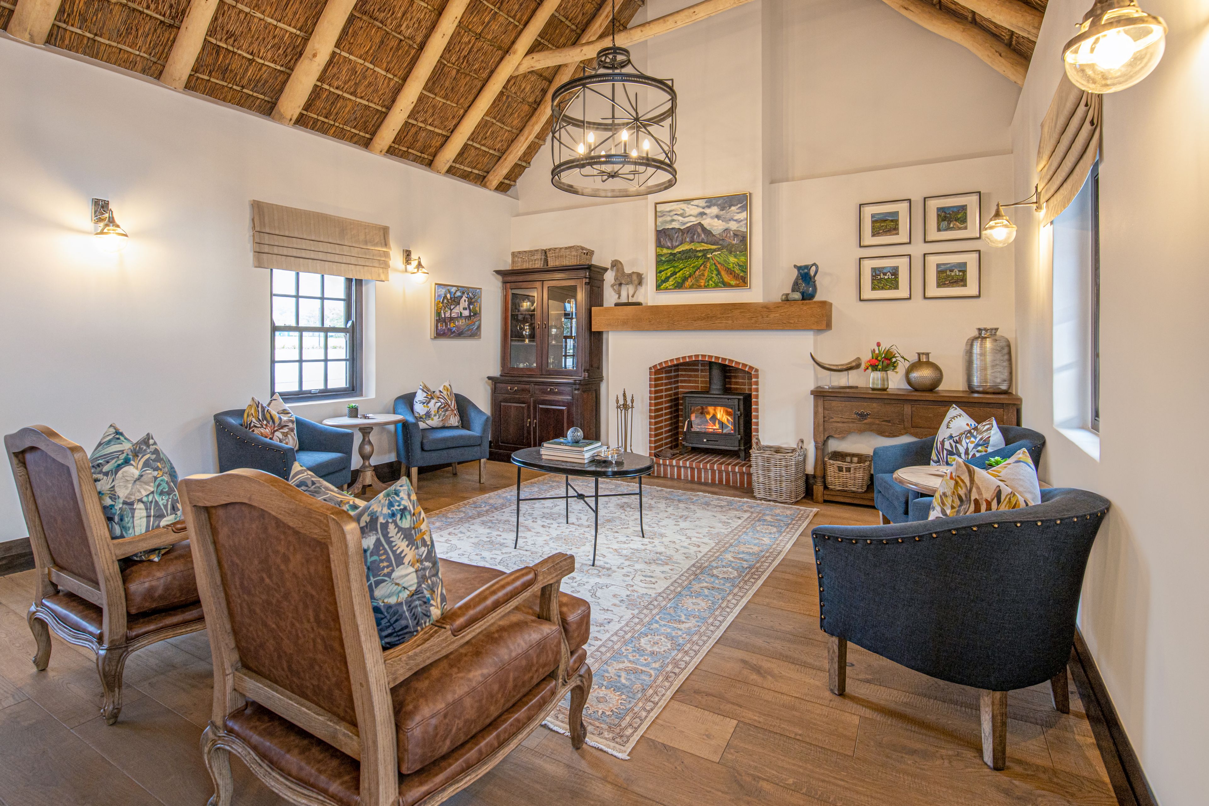 A spacious living room with a fireplace, wooden furniture, and a high ceiling.