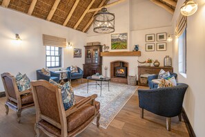 Un salón espacioso con chimenea, muebles de madera y un techo alto.