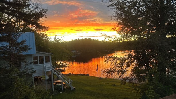 A house with a deck and a view of a lake at sunset.