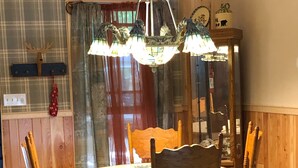 A dining area with a round wooden table, four chairs, and a chandelier.