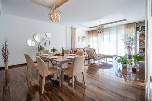 A modern dining area with a wooden table, beige chairs, and a chandelier. - A modern spacious elegant villa with pool in Pula with finely decorated two apartments connected with internal staircase. (Pula)