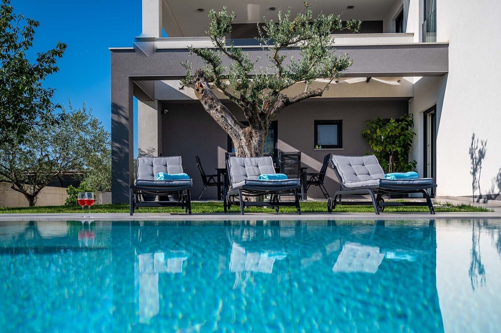 A modern poolside area with lounge chairs and a clear blue pool.