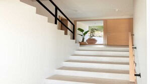 A staircase with white steps and black handrails, leading to a wooden door.