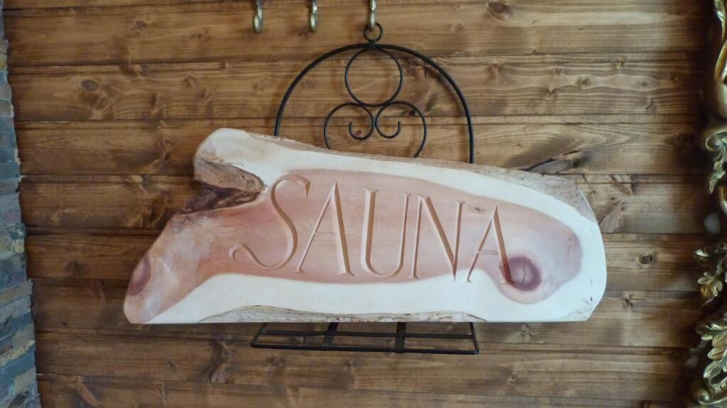 A wooden wall with a sign that reads "SAUNA" mounted on a metal stand.