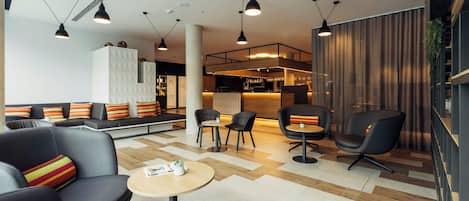 A modern lounge area with seating, tables, and a bar.