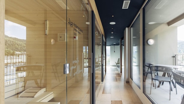 Een modern wellnesscentrum met glazen wanden, houten vloeren en uitzicht op een meer.