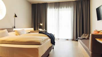 A hotel room with a large bed, a desk, a chair, a TV, and a window with curtains.