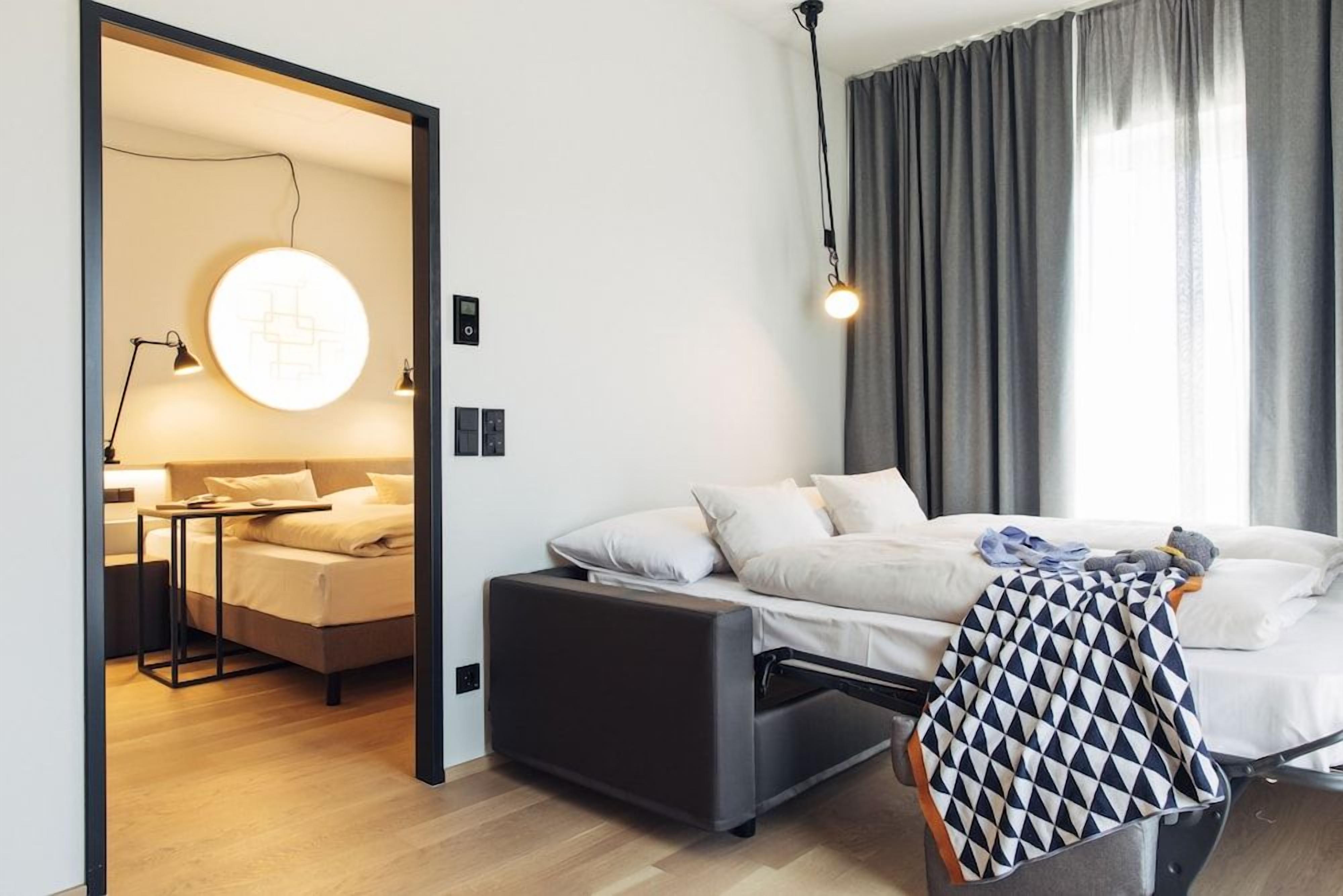 A modern bedroom with a bed, bedside table, and a circular light fixture.