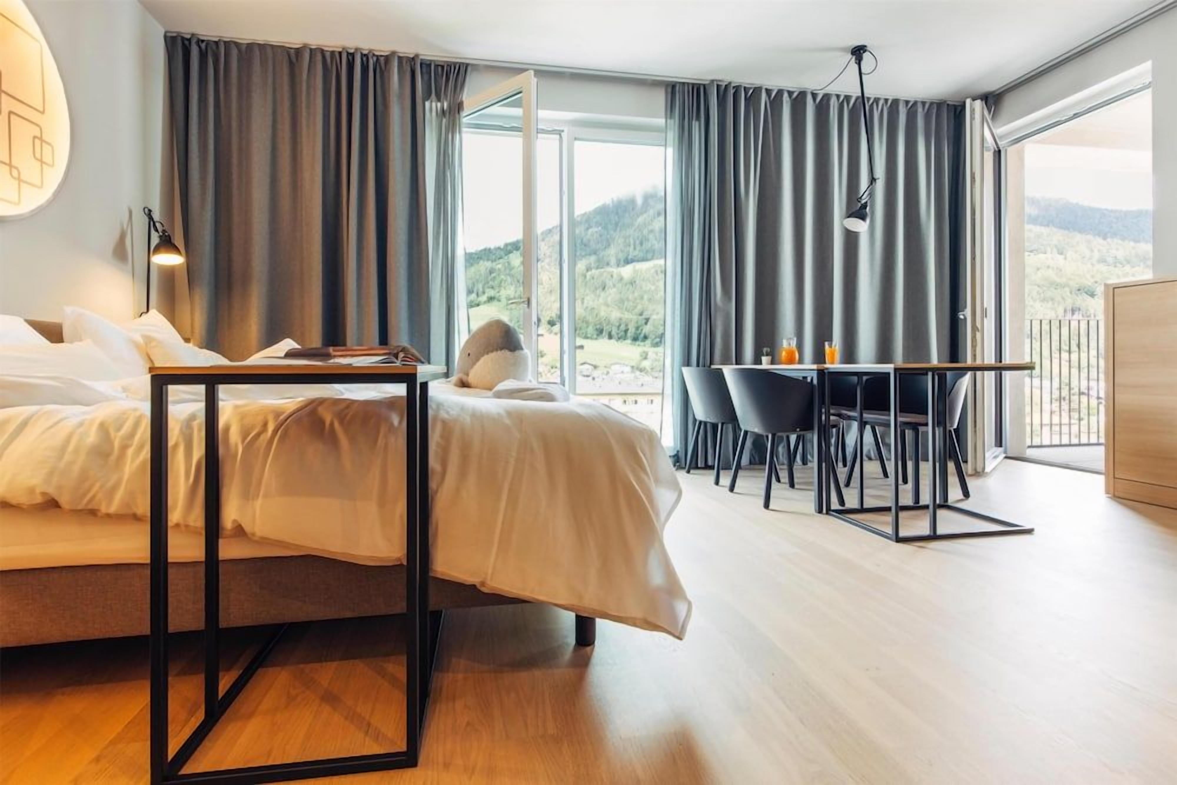 Un dormitorio con cama, escritorio y vistas al exterior.