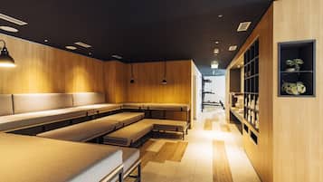 A modern interior with wooden panel walls, a central seating area with benches, pendant lighting, and a display shelf with items.
