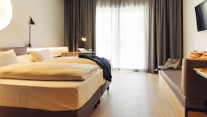 Een hotelkamer met een groot bed, een bureau, een stoel, een televisie en een raam met gordijnen.