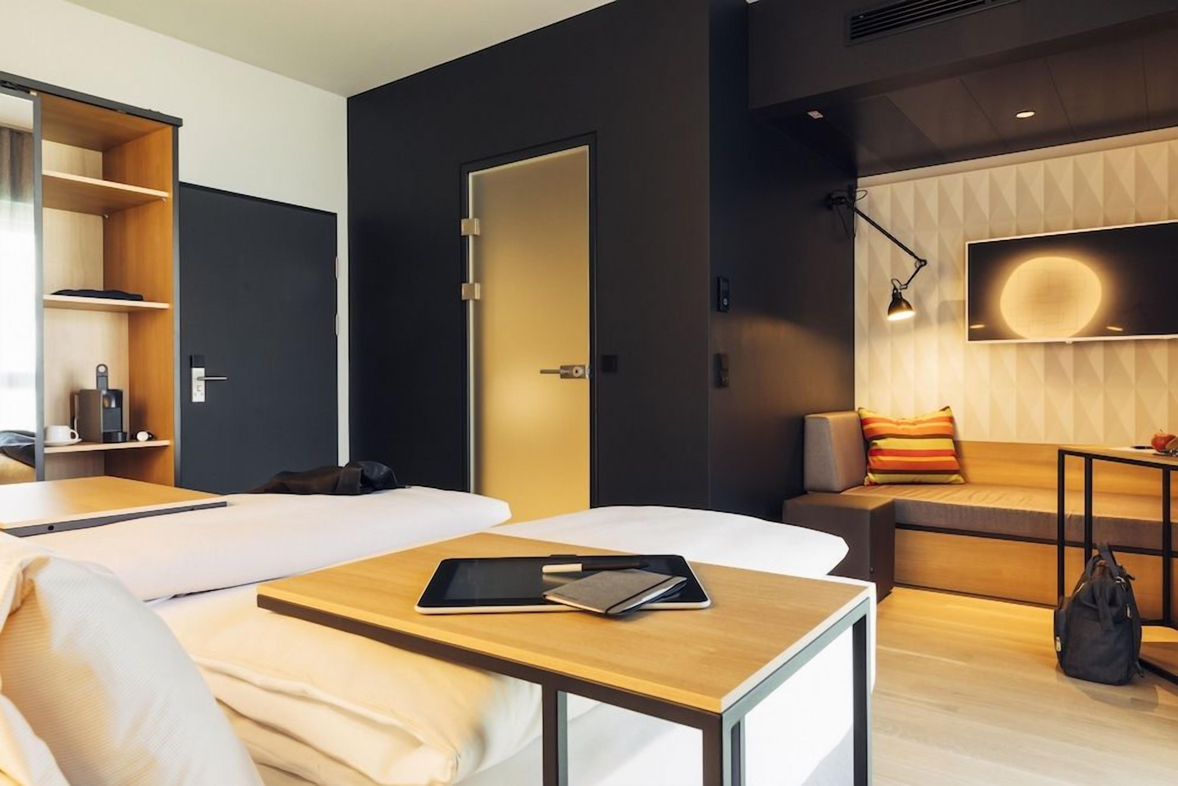 Una habitación de hotel moderna con cama, escritorio, sofá y televisión.