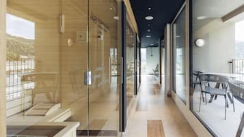 A modern spa with glass walls, wooden flooring, and a view of a lake.