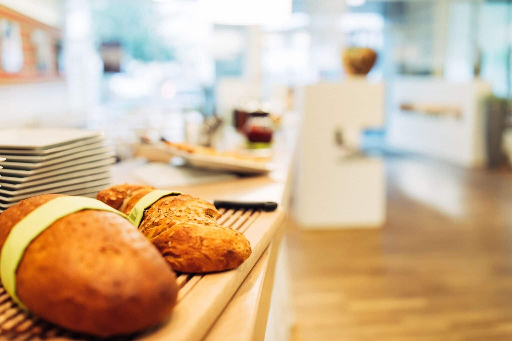 Un bufé de desayuno con panecillos y una pila de platos.