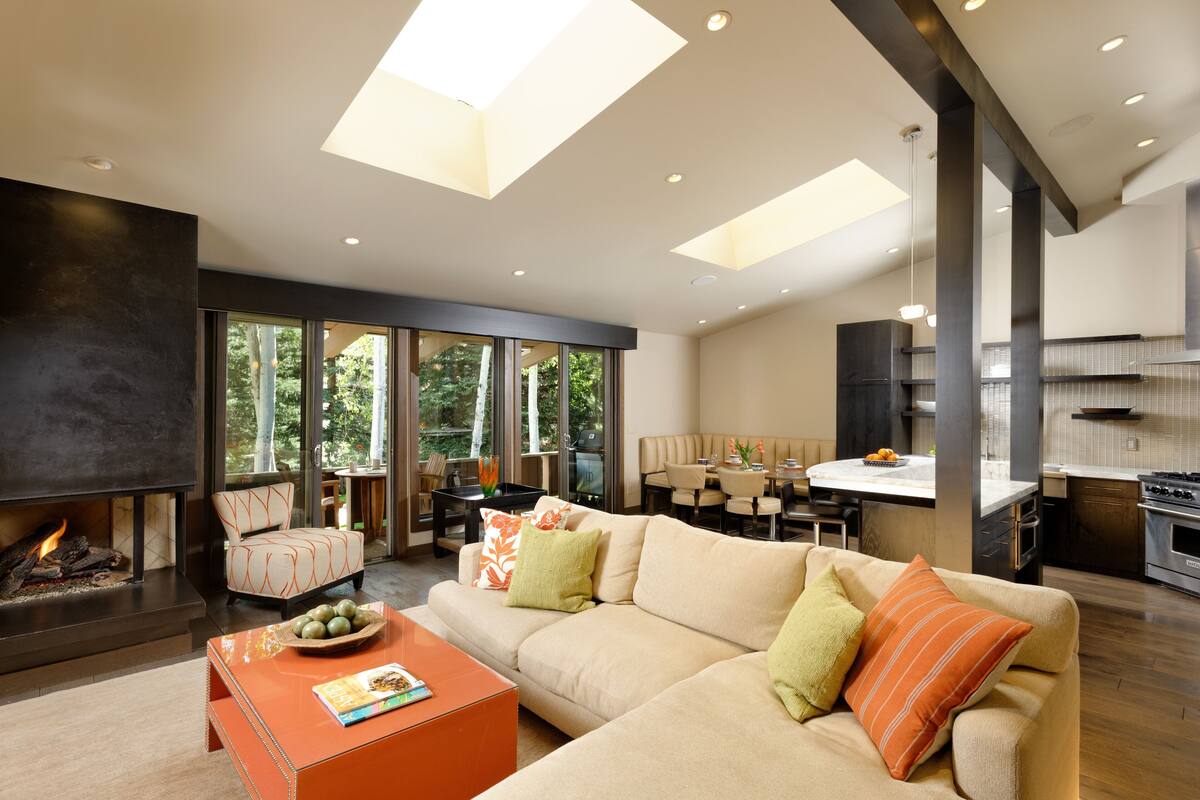 A modern living room with a fireplace, sofa, and dining area.