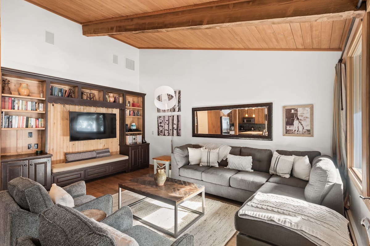 A cozy living room with a flat-screen TV, a bookshelf, a sofa, and a coffee table.