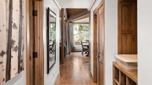 A hallway with wooden flooring, a dining area with a table and chairs, and a view of greenery outside. - Deluxe 2 Bedroom Apartments at Resort with Outdoor Pool & Hot Tub (Aspen)