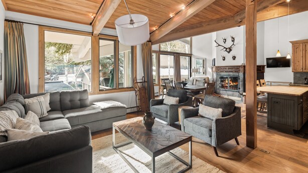 A spacious living area with a large sofa, armchairs, and a coffee table. There is a fireplace, wooden beams on the ceiling, and a television mounted on the wall. - Deluxe 2 Bedroom Apartments at Resort with Outdoor Pool & Hot Tub (Aspen)