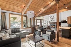 A spacious living area with a large sofa, armchairs, and a coffee table. There is a fireplace, wooden beams on the ceiling, and a television mounted on the wall. - Deluxe 2 Bedroom Apartments at Resort with Outdoor Pool & Hot Tub (Aspen)