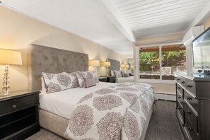 A bedroom with a large bed, bedside tables, a dresser, and a window with a view. - Comfortable & Modern 2 Bedroom Apartments - Right on the Slopes! (Aspen)
