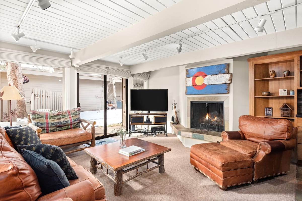A spacious living room with a leather sofa, a wooden coffee table, and a fireplace.