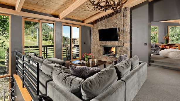 Una sala de estar moderna con chimenea de piedra, un sofá grande y un televisor montado en la pared.