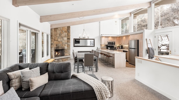 A modern open-plan living area with a fireplace, kitchen, and dining space. - Two Bedroom Apartments with One of a Kind Location on Slopes of Aspen Mountain! (Aspen)