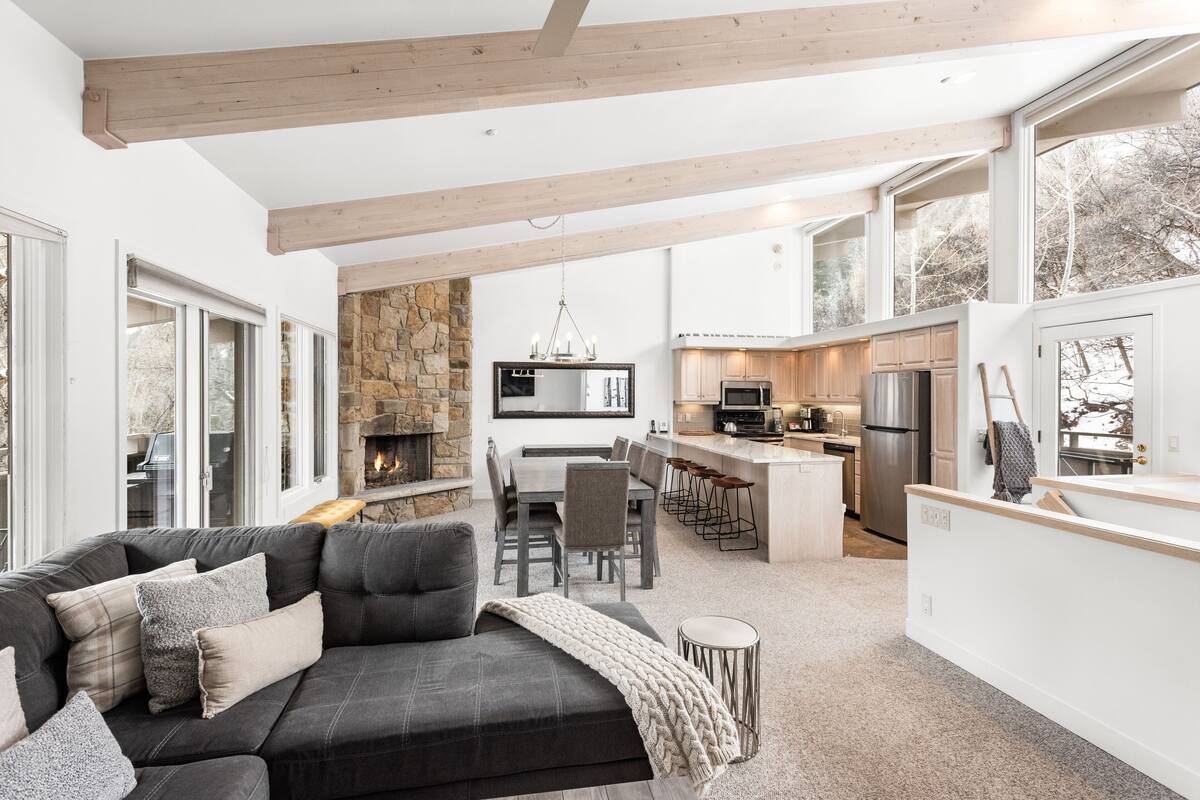 A modern open-plan living area with a fireplace, kitchen, and dining space.