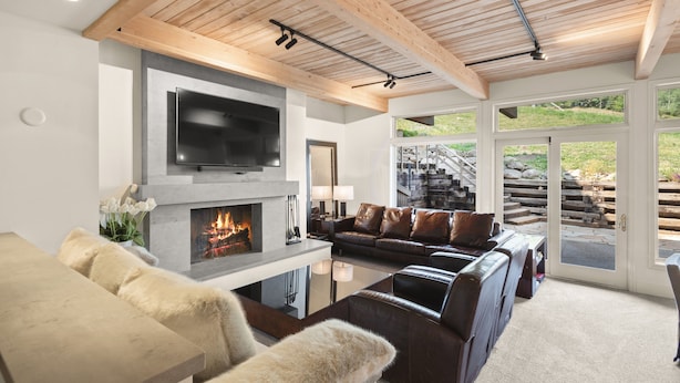 A modern living room with a fireplace, leather sofas, a flat-screen TV, and a view of a stone staircase leading outside. - Deluxe 3 & 4 Bedroom Aspen Apartments Next to Silver Queen Gondola (Aspen)
