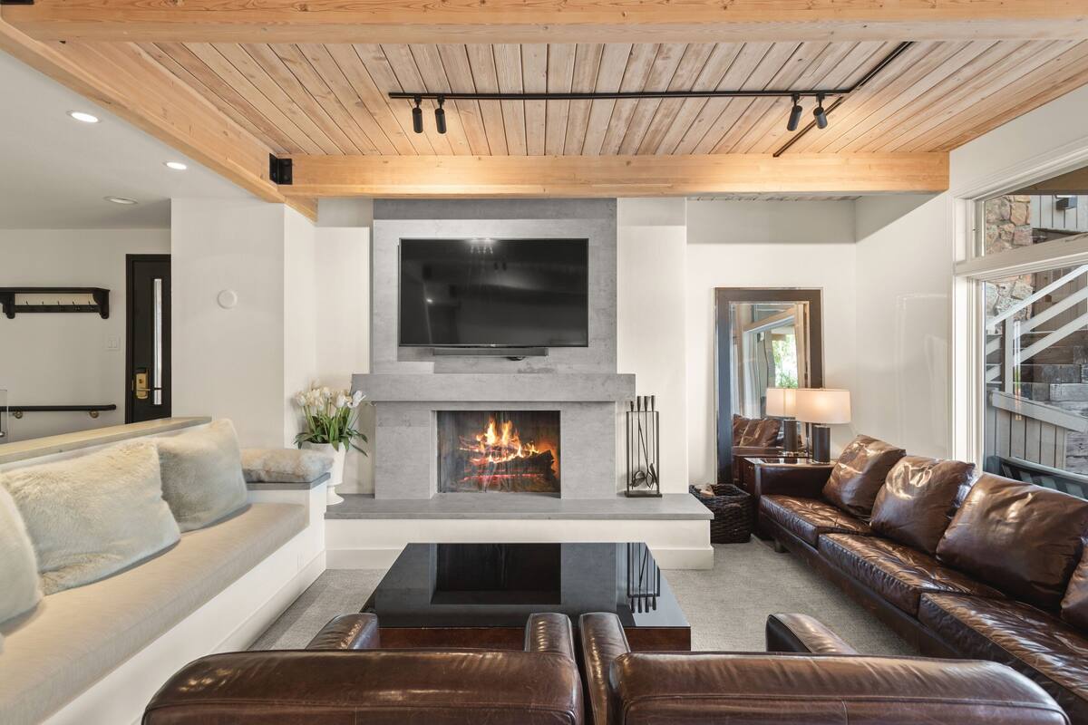 Ein modernes Wohnzimmer mit Kamin, Ledersofas und einem Flachbildfernseher.