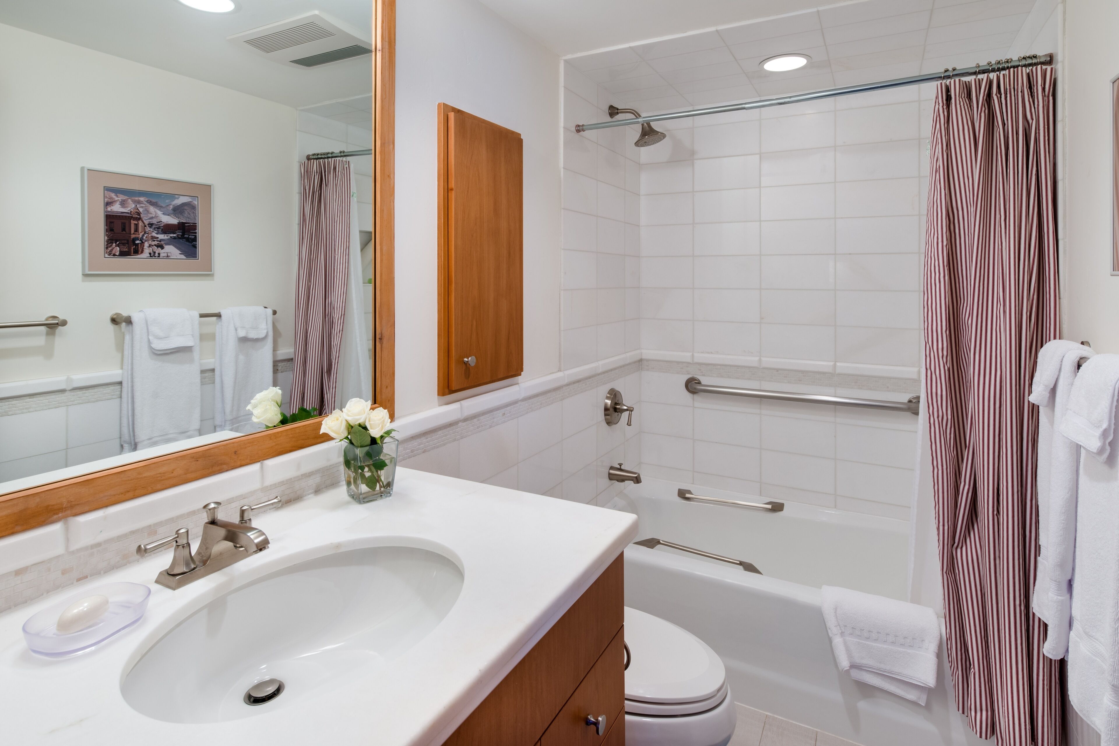 A modern bathroom with a sink, toilet, shower, and a large mirror.