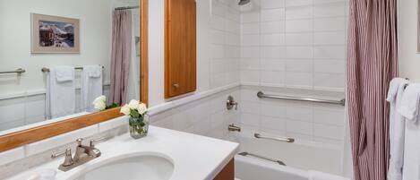 A modern bathroom with a sink, toilet, shower, and a large mirror.