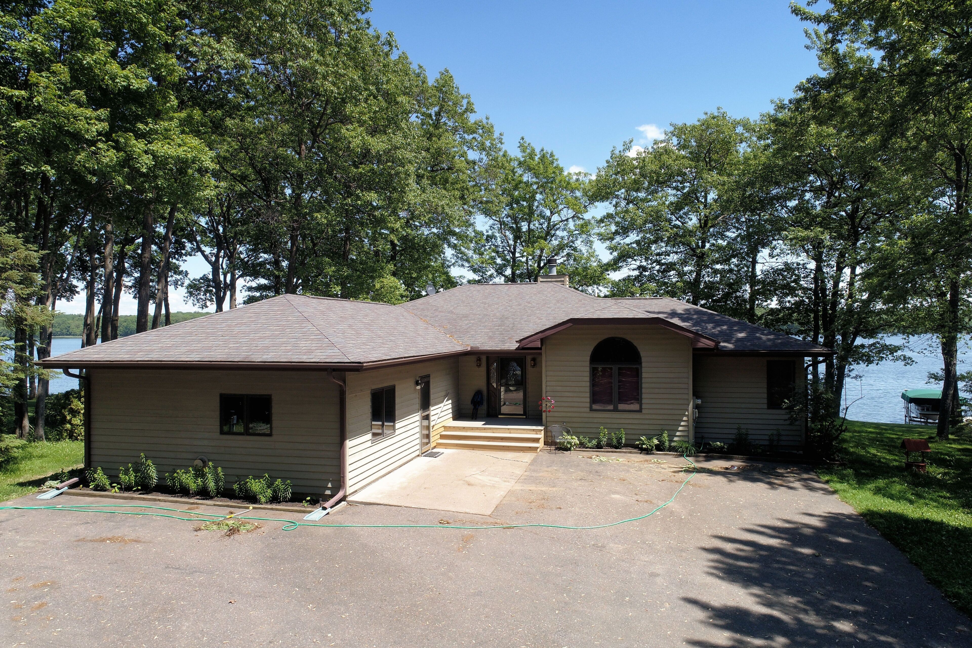 A two-story house with a front porch, a garage, and a driveway leading to a boat dock.