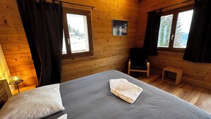 Una habitación de cabaña de madera con una cama, una silla y una pequeña mesa.