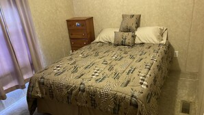 A bedroom with a bed, a wooden nightstand, and a window with curtains. - Quiet secluded private single wide mobile home  (Jasper)