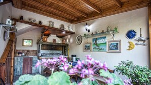 Una cocina rústica con vigas de madera, un lavabo de piedra y diversos utensilios de cocina en estantes.