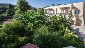 Un edificio residencial con balcón, rodeado de abundante vegetación y árboles.