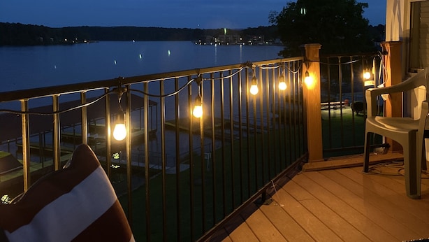 Une terrasse en bois avec une rambarde donnant sur une étendue d’eau, une chaise et une petite table.