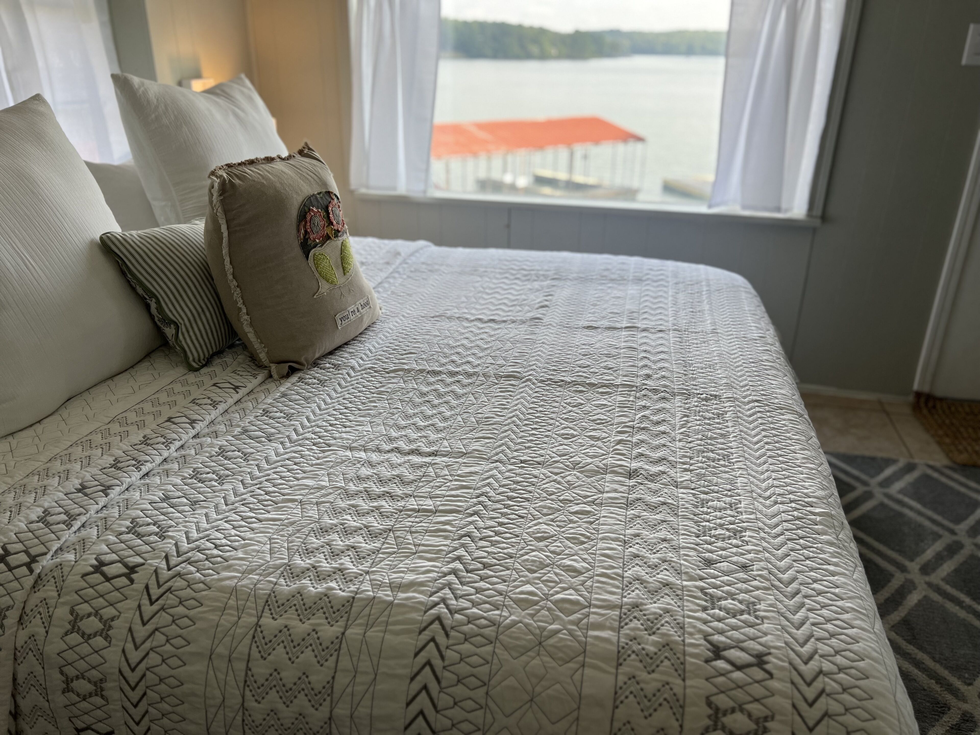 Una cama bien hecha con un edredón estampado y varias almohadas, incluyendo una con un parche.