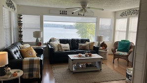 Un salon chaleureux avec un canapé en cuir noir, une table basse et une vue sur un lac.
