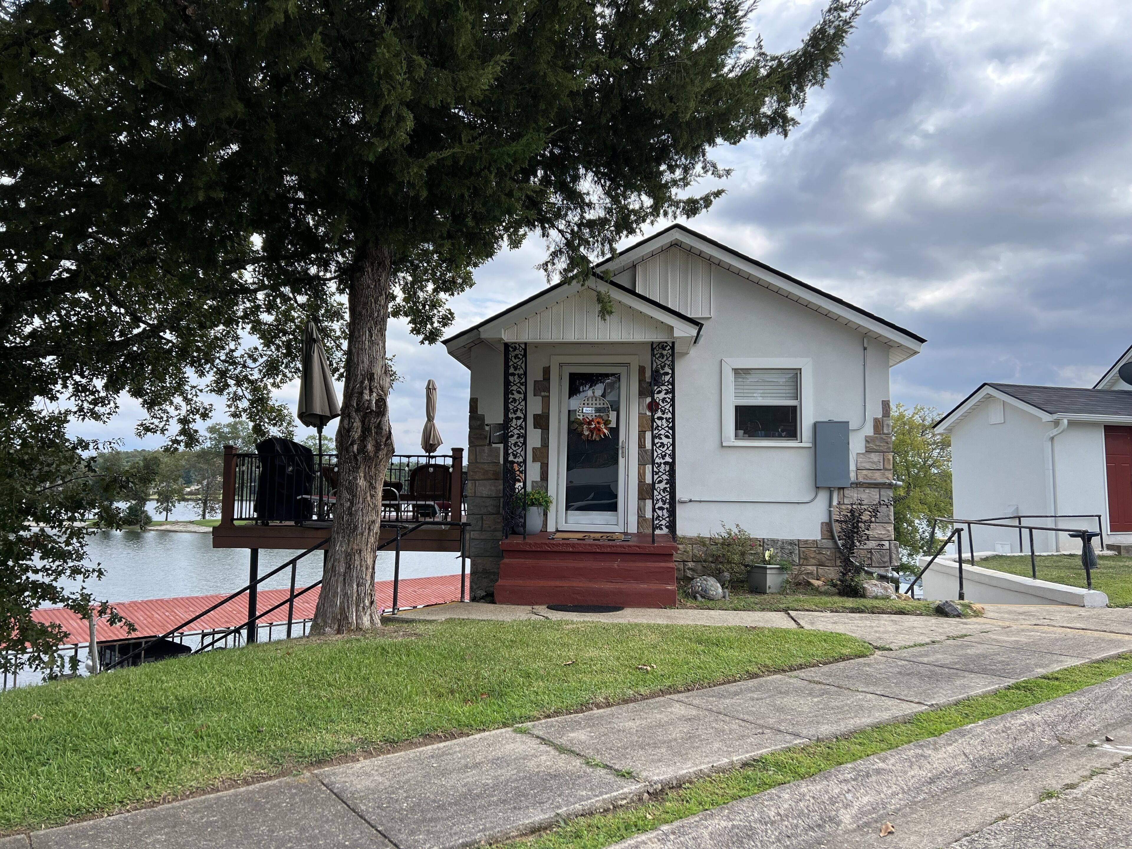 A house with a front porch, a small deck, and a view of a lake.