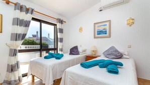 Habitación de hotel con dos camas, una ventana con cortinas, un cuadro y una lámpara.