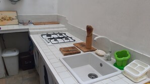 Una cucina compatta con fornello a gas, lavello e lavatrice.