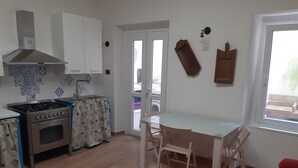 Una cucina compatta con piano cottura, forno e zona pranzo con tavolo e sedie.
