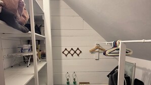 Una habitación pequeña con una cama litera, una tabla de planchar, un radiador y una alfombra colorida.